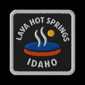 Puede incluir: Parche bordado con el texto "LAVA HOT SPRINGS IDAHO" en blanco sobre fondo negro. El diseño incluye una piscina azul con vapor blanco, un sol amarillo y un borde naranja. El parche tiene un borde cosido blanco.