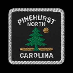 May include: Embroidered patch featuring the text "PINEHURST NORTH CAROLINA" in white, with a green pine tree and a gold sun on a black background. The patch has a white border.