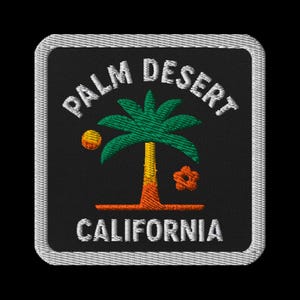 May include: Embroidered patch featuring a palm tree with green fronds, a yellow trunk, and orange accents. The text "PALM DESERT CALIFORNIA" is stitched in white on a black background, framed by a silver border.
