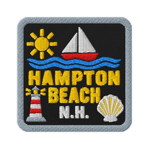 Puede incluir: Un parche bordado cuadrado con fondo negro y borde gris claro. Presenta un sol amarillo, un velero blanco y rojo sobre olas azules, un faro rojo y blanco, una concha marina blanca y el texto amarillo HAMPTON BEACH N.H.