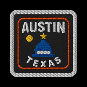Könnte beinhalten: Gestickter Aufnäher mit dem Schriftzug "AUSTIN" über "TEXAS". Das Design zeigt eine blaue Kuppel, einen goldenen Stern und einen gelben Kreis auf schwarzem Hintergrund, umrahmt von einem orangefarbenen Rand und weißen Nähten.