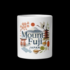 May include: White ceramic mug featuring a design with Mount Fuji, cherry blossoms, a crane, and a pagoda. The text "Mount Fuji Japan" is prominently displayed. The design includes a red sun, waves, and a bowl of noodles.