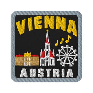 May include: A square embroidered patch with a black background and a gray border. The text VIENNA is in yellow at the top and AUSTRIA is in white at the bottom. It features a tan building, a white church with a red roof, and a white ferris wheel.