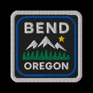 May include: Embroidered patch featuring the text "BEND OREGON" above a mountain range and evergreen trees. A yellow star is to the right of the mountains. The patch has a blue border and a white stitched edge.