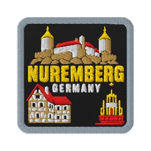 May include: A square embroidered patch with a grey border on a black background. It features a yellow castle, a half-timbered house with a red roof, and a yellow fountain. The text reads NUREMBERG GERMANY in yellow and white capital letters.