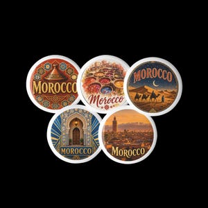 Op de afbeelding: Vijf ronde magneten met Marokkaanse thema's. Eén toont een tajine met geometrische patronen, één kleurrijke verfbaden, één een woestijnkaravaan onder een maansikkel, één een boogvormige deuropening en één een stadsgezicht met de tekst Marokko.