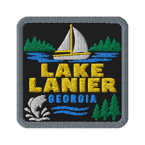 Peut inclure: Un écusson brodé carré avec un fond noir et une bordure grise. Il représente un voilier blanc sur une eau bleue, des pins verts, et le texte jaune LAKE LANIER au-dessus du texte bleu GEORGIA, avec un motif de poisson blanc qui saute.
