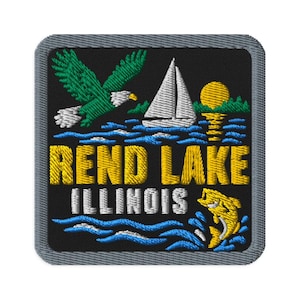 Op de afbeelding: Een vierkante geborduurde patch met een zwarte achtergrond en een grijze rand. Het toont een groene adelaar, een wit zeilbootje, een gele zon en een gele vis die uit blauw water springt. De tekst luidt REND LAKE in geel en ILLINOIS in wit.