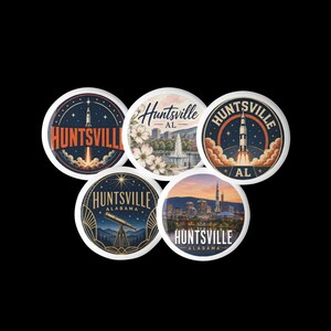 May include: Five circular pin-back buttons featuring Huntsville, Alabama themes. Designs include a rocket launch, a city skyline with a fountain and flowers, a second rocket launch, a telescope under a starry sky, and a sunset city skyline with a rocket.