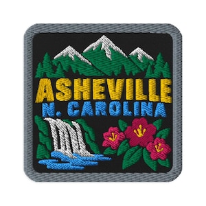 Può includere: Una toppa ricamata quadrata con sfondo nero che raffigura una catena montuosa con cime bianche, pini verdi, una cascata e fiori rosa. Il testo ASHEVILLE N. CAROLINA è ricamato in filo giallo e blu con un bordo di colore grigio.