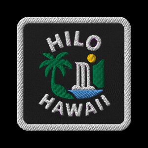 May include: Embroidered patch with the words "HILO HAWAII" in white, arched above and below a tropical scene. The scene includes a green palm tree, a waterfall, a yellow sun, and blue water, all on a black background.