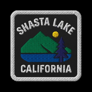 Puede incluir: Parche bordado con las palabras "SHASTA LAKE CALIFORNIA" en blanco. El parche presenta una cordillera verde, un sol amarillo, un lago azul y un árbol azul oscuro sobre un fondo negro.