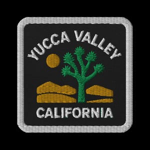 Può includere: Toppa ricamata con la scritta "YUCCA VALLEY CALIFORNIA" in bianco. Presenta un albero di Giosuè, un sole e un paesaggio desertico in verde, giallo e arancione su sfondo nero, con un bordo bianco.