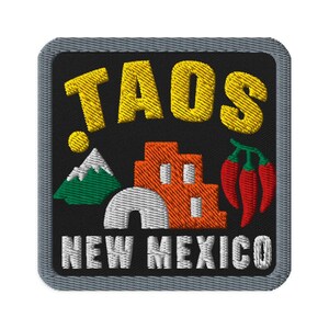 Puede incluir: Un parche bordado cuadrado con fondo negro y borde gris. El texto TAOS está en amarillo y NEW MEXICO en blanco. El diseño presenta una montaña verde, un sol amarillo, un edificio de adobe naranja y tres chiles rojos.