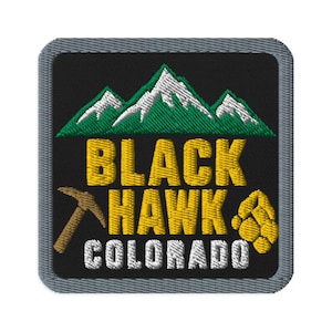 May include: A square embroidered patch with a black background and a gray border. It features green and white mountains above the yellow text BLACK HAWK, a brown pickaxe, a yellow cluster of gold nuggets, and the white text COLORADO below.