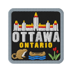 Può includere: Una toppa ricamata quadrata con bordo grigio su sfondo nero. Presenta una rappresentazione bianca e gialla degli edifici del Parlamento di Ottawa, il testo OTTAWA ONTARIO, un castoro marrone, una canoa marrone su acqua blu e tulipani rossi.