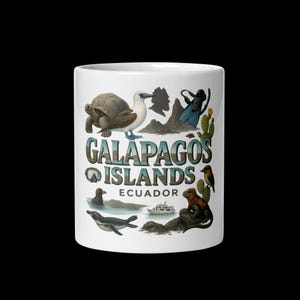 May include: White ceramic mug with a colourful illustration of the Galapagos Islands. The design includes various animals, cacti, and the text "Galapagos Islands Ecuador". A great gift for nature lovers.