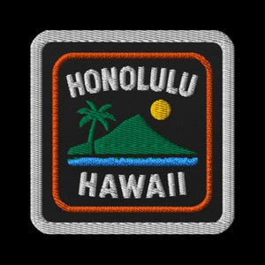 May include: Embroidered patch featuring a Hawaiian landscape with a palm tree, mountain, and sun. The patch reads "HONOLULU" above and "HAWAII" below the image. The design is framed by an orange border and a silver edge.