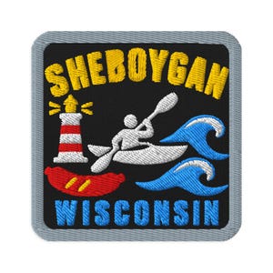 May include: A square embroidered patch with a black background and a grey border. It features the yellow text SHEBOYGAN above a white lighthouse, a white kayak with a person paddling, two blue waves, a red sausage, and blue text WISCONSIN.