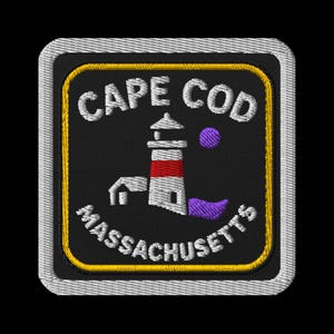 Peut inclure: Écusson brodé avec un phare à rayures rouges et blanches, un accent violet et le texte "CAPE COD MASSACHUSETTS" en blanc. L'écusson a un fond noir, une bordure jaune et un bord cousu blanc.