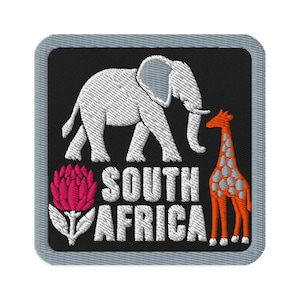 May include: A square embroidered patch with a black background and a grey border. It features a white elephant, an orange and white giraffe, and a pink protea flower. The text SOUTH AFRICA is embroidered in white letters in the centre.