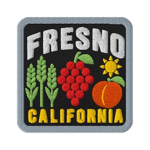 Może przedstawiać: Kwadratowa haftowana naszywka z czarnym tłem i jasnoszarą obwódką. Zawiera biały napis FRESNO u góry i żółty napis CALIFORNIA u dołu. Wzór przedstawia zielone kłosy pszenicy, czerwone winogrona oraz brzoskwinię ze słońcem.