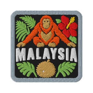 May include: A square embroidered patch with a black background featuring an orange orangutan, a red hibiscus flower, green palm leaves, and a brown durian fruit. The word MALAYSIA is stitched in white capital letters across the centre.