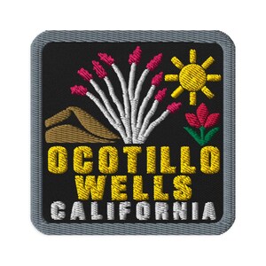 Può includere: Una toppa ricamata quadrata con sfondo nero e bordo grigio. Presenta una duna di sabbia color cuoio, una pianta di ocotillo bianca con punte rosa, un sole giallo e un fiore rosso. Il testo OCOTILLO WELLS CALIFORNIA è ricamato in giallo e bianco.
