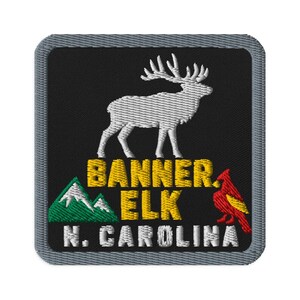 Puede incluir: Un parche bordado cuadrado con borde gris sobre fondo negro. Presenta la silueta de un alce blanco sobre el texto amarillo BANNER ELK, un gráfico de montaña verde, un pájaro cardenal rojo y el texto blanco N. CAROLINA.