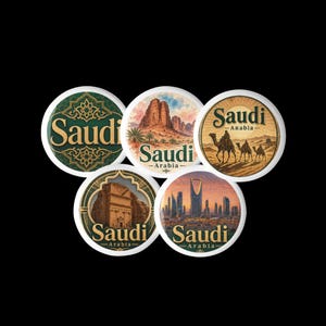 May include: Five circular pins featuring Saudi Arabia themes. One has green patterns with the text Saudi, another shows desert rock formations, a third depicts camels in a desert, a fourth shows a stone monument, and the fifth displays a city skyline.