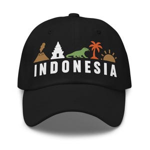 May include: A black baseball cap featuring a graphic design with a brown volcano, a white temple, a green Komodo dragon, an orange palm tree, and a brown sun. Below the icons, the word INDONESIA is printed in bold, white, capital letters.