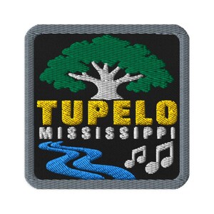 May include: A square embroidered patch with a black background and a gray border. It features a green tree with a white trunk, the yellow text TUPELO, the white text MISSISSIPPI, a blue winding river, and two white musical notes.