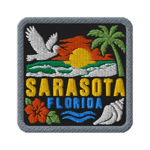 Puede incluir: Un parche bordado cuadrado con fondo negro que muestra un pájaro blanco, un sol amarillo, un atardecer naranja, una palmera verde y olas blancas. El texto SARASOTA FLORIDA está en amarillo y azul, con un hibisco rojo y una concha blanca.