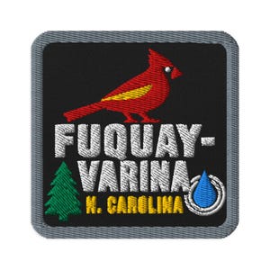 May include: A square embroidered patch with a black background and a grey border. It features a red cardinal bird with a yellow wing, a green pine tree, a blue water drop icon, and white text reading FUQUAY-VARINA and yellow text N. CAROLINA.