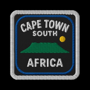 May include: Embroidered patch featuring the text "CAPE TOWN SOUTH AFRICA" in white, with a green mountain and yellow sun design. The patch has a black background, a blue border, and a white stitched edge.