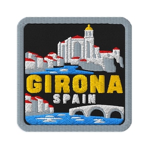 May include: A square embroidered patch with a black background featuring a white and red architectural scene of Girona, Spain. The text GIRONA SPAIN is stitched in yellow and white. A blue river and a white stone bridge are depicted below.