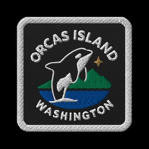 Könnte beinhalten: Gestickter Aufnäher mit schwarzem Hintergrund, der einen springenden Orca in Schwarz und Weiß über blauem Wasser und grünen Bergen zeigt. Der Text "Orcas Island Washington" ist weiß, mit weißem Rand.