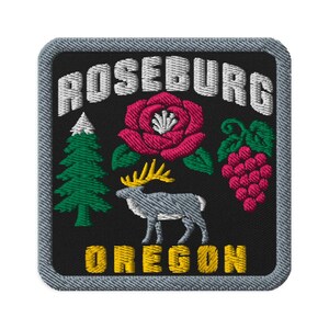 May include: A square embroidered patch with a black background and a gray border. It features the white text ROSEBURG at the top and OREGON at the bottom in yellow. The design includes a green pine tree, a pink rose, and a cluster of grapes.