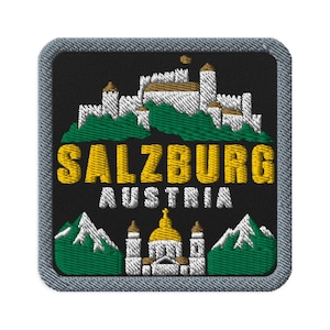 Puede incluir: Un parche bordado cuadrado con borde gris sobre fondo negro. Presenta un castillo blanco sobre una colina verde, el texto amarillo SALZBURG, el texto blanco AUSTRIA y una catedral blanca con cúpula dorada flanqueada por montañas verdes.