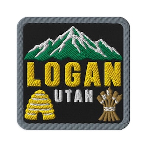 May include: A square embroidered patch with a black background and a gray border. It features a green and white mountain range above the yellow text LOGAN and white text UTAH. A yellow beehive and a brown wheat sheaf are at the bottom corners.