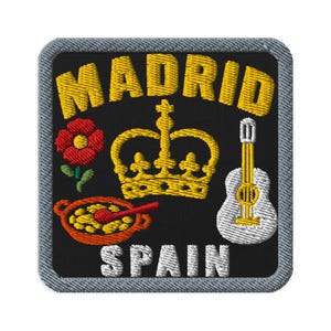 May include: A square embroidered patch with a black background and a gray border. It features the yellow text MADRID at the top and SPAIN at the bottom. The design includes a red flower, a yellow crown, a bowl of yellow food, and a white guitar.