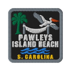 Puede incluir: Un parche bordado cuadrado con fondo negro que muestra una palmera verde, una hamaca blanca y un pelícano blanco con pico naranja. El texto dice PAWLEYS ISLAND BEACH en blanco y S. CAROLINA en amarillo sobre unas olas azules.