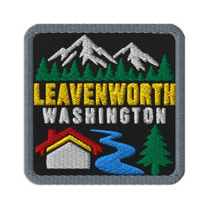 May include: A square embroidered patch with a black background featuring white mountain peaks above green pine trees. The text LEAVENWORTH WASHINGTON is centred in yellow and white. Below, a red and white house, a blue river, and a green tree.