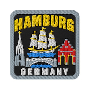 Puede incluir: Un parche bordado cuadrado con fondo negro y borde gris. El texto HAMBURG aparece en amarillo en la parte superior y GERMANY en blanco en la parte inferior. Incluye un velero blanco, una torre de iglesia gris, un puente gris y un edificio rojo.