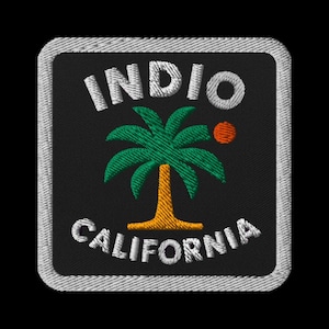 May include: Embroidered patch featuring the text "INDIO CALIFORNIA" in white, arched around a green palm tree with an orange sun on a black background. The patch has a white border.