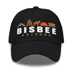 Può includere: Un cappellino da baseball nero con un design grafico che mostra una montagna verde, un castelletto di estrazione beige, un asino beige, un sole arancione e un carrello da miniera marrone. Sotto, il testo riporta BISBEE in bianco e ARIZONA in beige.