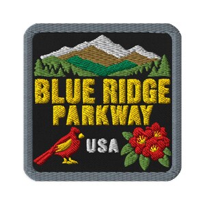 May include: A square embroidered patch with a black background and a gray border. It features a mountain range, green trees, and the yellow text BLUE RIDGE PARKWAY. Below, a red cardinal, the white text USA, and a cluster of red flowers appear.