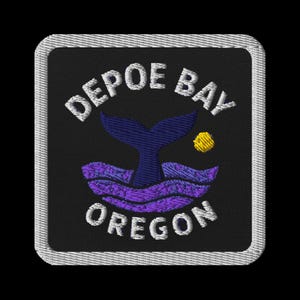 May include: Embroidered patch featuring the words "Depoe Bay Oregon" in white, arched over a whale tail and waves in purple and blue. A yellow sun is also present. The patch has a black background and a white border.
