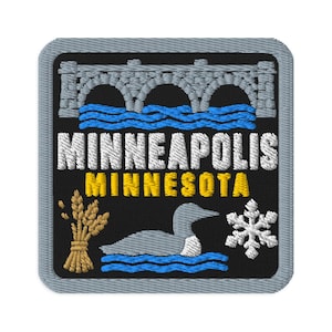 Könnte beinhalten: Ein quadratischer Stickaufnäher mit grauem Rand auf schwarzem Grund. Er zeigt eine graue Steinbrücke über blauem Wasser, den weißen Schriftzug MINNEAPOLIS, gelben Schriftzug MINNESOTA, eine goldene Weizengarbe, einen grauen Eistaucher und eine weiße Schneeflocke.