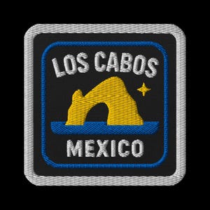 May include: Embroidered patch with the text "LOS CABOS MEXICO" in white. The design features a yellow archway and a star on a black background, with a blue border and a silver edge.